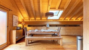 Un intérieur en bois comprenant une table à manger pour quatre personnes, un canapé et un coin cuisine avec des placards.