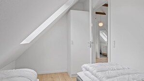 Ett modernt sovrum med ett sluttande tak, ett takfönster och utsikt över ett angränsande köksområde.