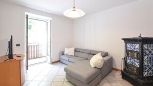 A living room with a grey sofa, a wooden cabinet, a television, and a decorative cabinet with blue and white patterns.