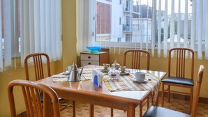 Ein Essbereich mit einem Holztisch, gedeckt für vier Personen, umgeben von Stühlen und einem Fenster mit Jalousien.