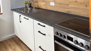 A kitchen with a wooden backsplash, a stainless steel stove, and a sink. - old town residence (Weißenhorn)