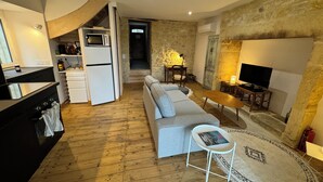 A compact living space with a kitchen, a sofa, a TV, and a small dining area. - Bezenac grocery store (Castels et Bézenac)