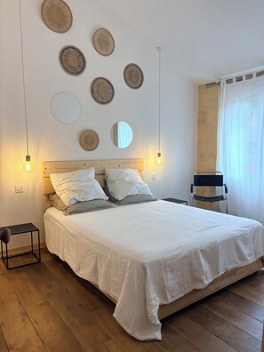 A neatly made bed with white linens, a wooden headboard, and a bedside table with a lamp. - Bezenac Grocery Store (Castels et Bézenac)