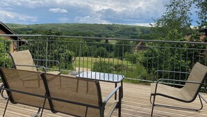 A balcony with two wicker chairs and a small table, overlooking a lush green landscape and hills. - Bezenac grocery store (Castels et Bézenac)
