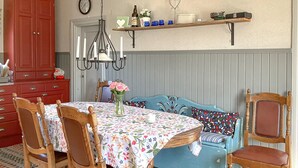 A dining area with a floral tablecloth, wooden chairs, a blue upholstered bench, and a chandelier. - 2 bedroom stunning home in Nås (Nås)