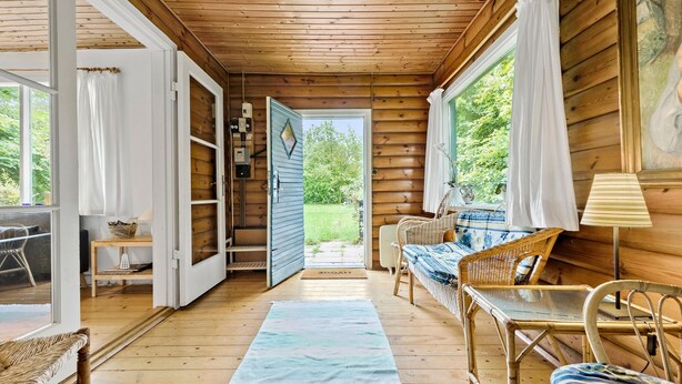 A cozy cabin interior with a wooden floor, wicker furniture, and a view of the outdoors. - 3 bedroom amazing home in Gilleleje (Gilleleje)