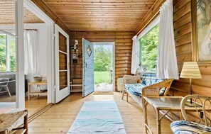 A cozy cabin interior with a wooden floor, wicker furniture, and a view of the outdoors. - 3 bedroom amazing home in Gilleleje (Gilleleje)