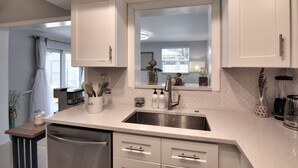 A modern kitchen with white cabinets, a stainless steel sink, and a countertop with various kitchen items.