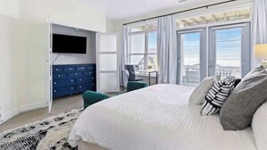 A bedroom with a bed, a TV, a dresser, and a balcony with a view. - Ocean Views-Private Heated Pool & Hot Tub-3 Kings! (Carolina Beach)