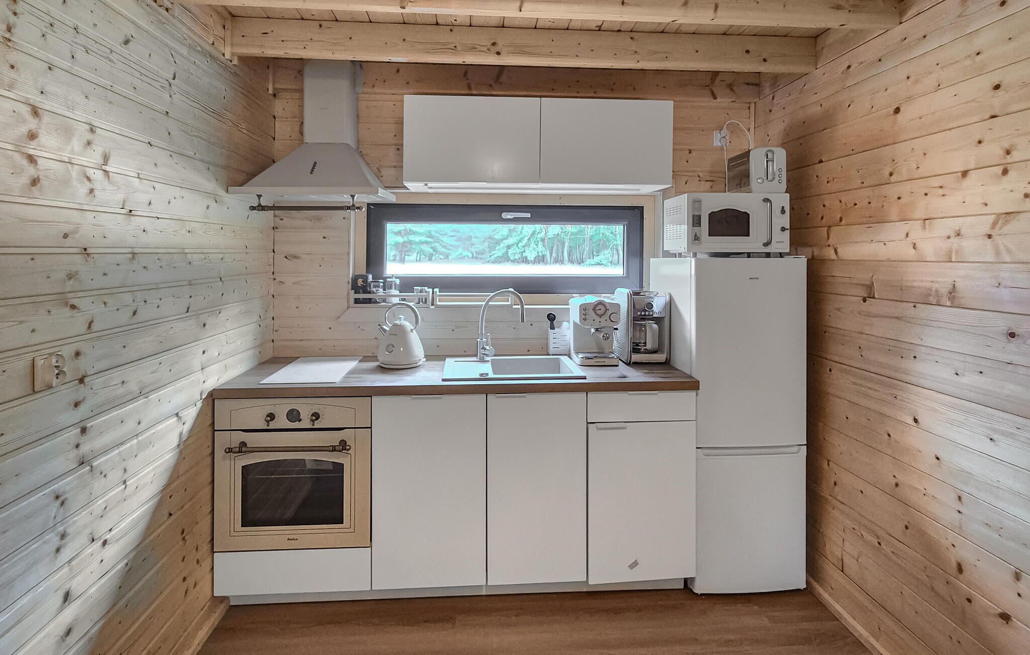 Una cocina compacta con ventana, estufa, fregadero y microondas.