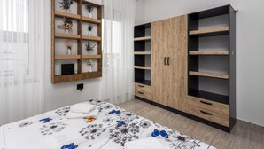 Une chambre à coucher comprenant un lit, une armoire en bois avec plusieurs étagères et une étagère murale agrémentée d’objets décoratifs.