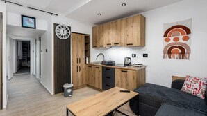 Une cuisine moderne avec des meubles en bois, une horloge noire et une machine à café.