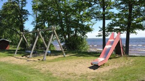 A playground with a swing set and a slide, located near a body of water.