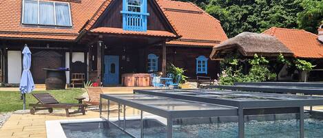 Uma casa de madeira tradicional com telhado vermelho, piscina e área de estar ao ar livre.