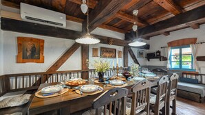 Un comedor rústico con muebles de madera, una mesa dispuesta para una comida, y vistas al exterior a través de una ventana.