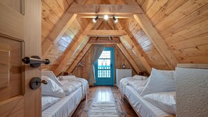 Un dormitorio acogedor en el ático con dos camas, vigas de madera, techo inclinado y una puerta azul.