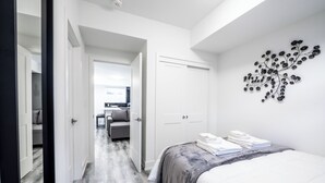 A bedroom with a bed, a wardrobe, a door, and a wall-mounted decoration. - Cozy 1BR with Parking, Only 7 Mins to The Falls and Sleeps 3! (Niagara Falls)