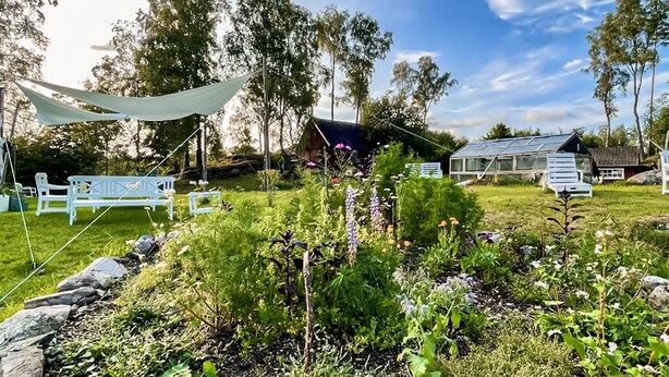 A garden with a white bench, a greenhouse, and a wooden cabin. - 2 bedroom gorgeous home in Hallaryd (Hallaryd)