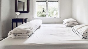 A bedroom with a bed, a bedside table, a mirror, and a window with a view of greenery. - 2 bedroom gorgeous home in Hallaryd (Hallaryd)