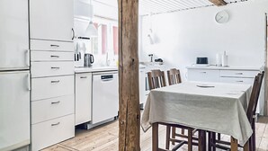A compact kitchen with white cabinetry, a wooden dining table, and a clock on the wall. - 2 bedroom gorgeous home in Hallaryd (Hallaryd)