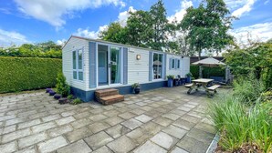 A mobile home with a patio area, a wooden bench, and potted plants. - Stunning (sta)caravan in Tzummarum (Tzummarum)