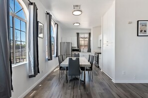 A modern kitchen with a central island, white cabinetry, and a large window with curtains.