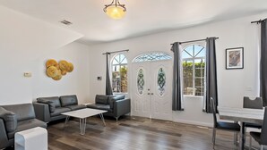 Una sala de estar moderna con un sofá gris, una mesa de centro blanca y una zona de comedor con una mesa y sillas.