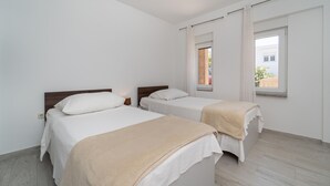 Una camera da letto con due letti, una finestra con tende e vista sull'esterno.