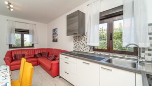Una cucina moderna con un divano rosso, mobili bianchi e un'ampia finestra.