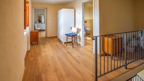 A spacious hallway with wooden flooring, a white wardrobe, a blue chair, and a small wooden table. - 3 bedroom pet friendly home in Barga (Barga)