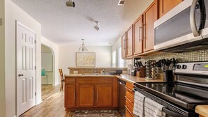 Une cuisine avec des meubles en bois, une cuisinière en acier inoxydable et un four à micro-ondes.