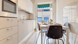 Una cocina moderna con armarios blancos, horno empotrado y comedor con mesa y sillas.