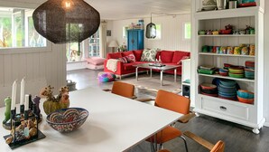 Een eetruimte met een witte tafel, oranje stoelen en een decoratieve schaal.