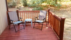 Eine Holzterrasse mit zwei Stühlen und einem Tisch.