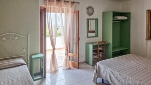 A bedroom with two beds, a green wardrobe, a small desk, and a window with sheer curtains. - 1 bedroom awesome home in Vieste (Vieste)