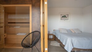 A bedroom with a bed, a chair, and a wooden wardrobe. - Beautiful home in Dobrenici with sauna (Dobrenici)