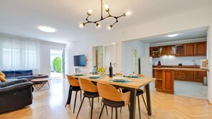 Un salon moderne comprenant un canapé, une table à manger pour quatre personnes et un coin cuisine avec des meubles en bois et un four encastré.