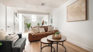 A modern living room with a brown sofa, a grey armchair, and a round coffee table with a plant.