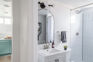 Une salle de bain moderne avec un lavabo blanc, un miroir et une douche.