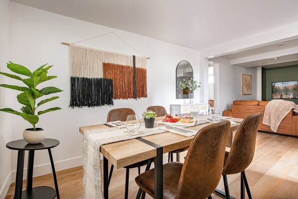 Un espace repas moderne avec une table en bois, des chaises marron et une plante en pot.