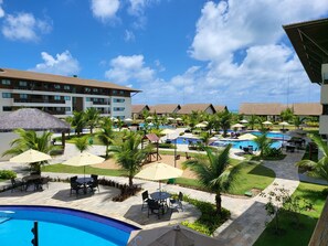 Ein Resort mit mehreren Swimmingpools, Sitzgelegenheiten im Freien und Palmen.
