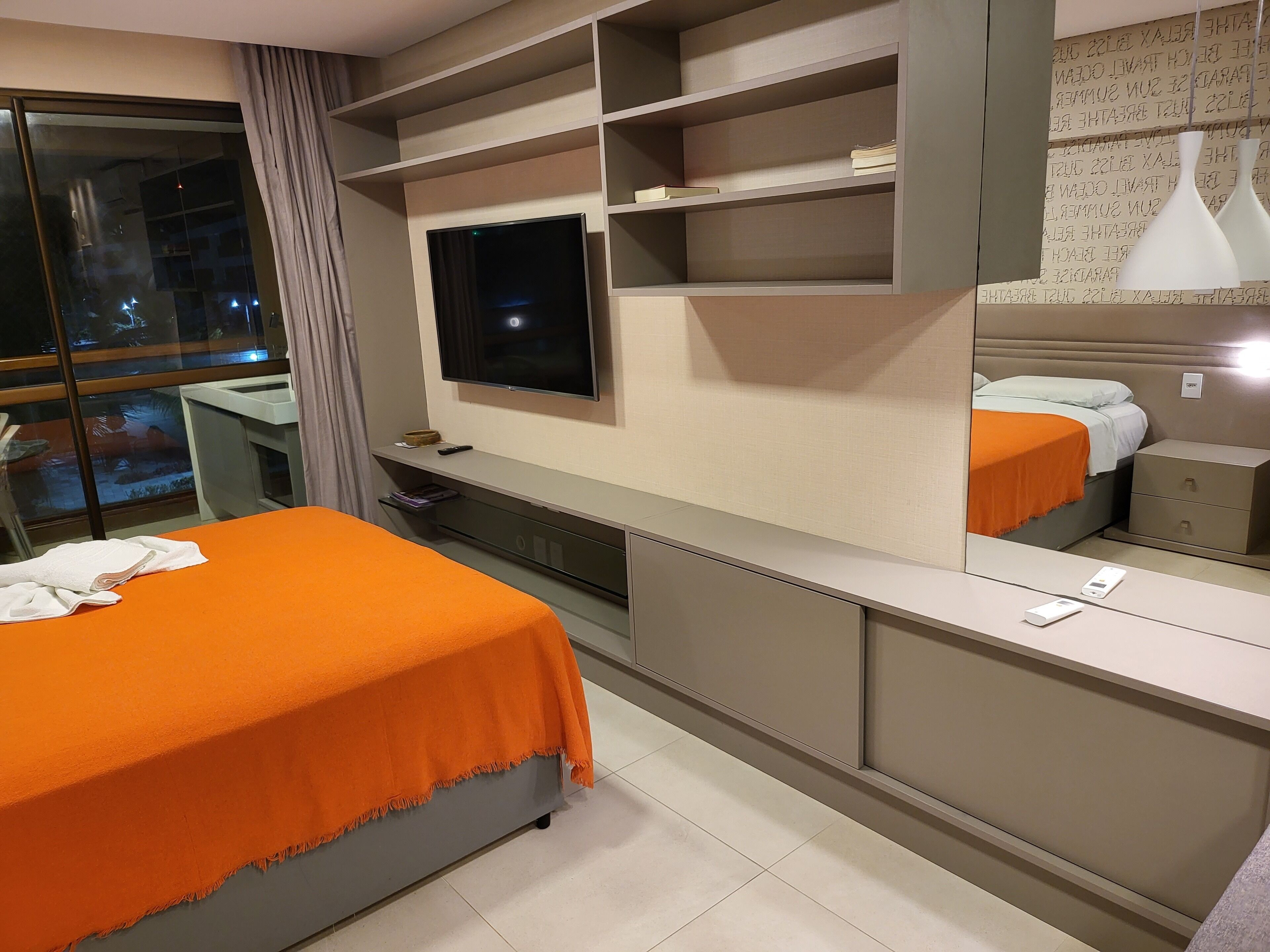 Een hotelkamer met een bed, een televisie, een bureau en een nachtkastje.