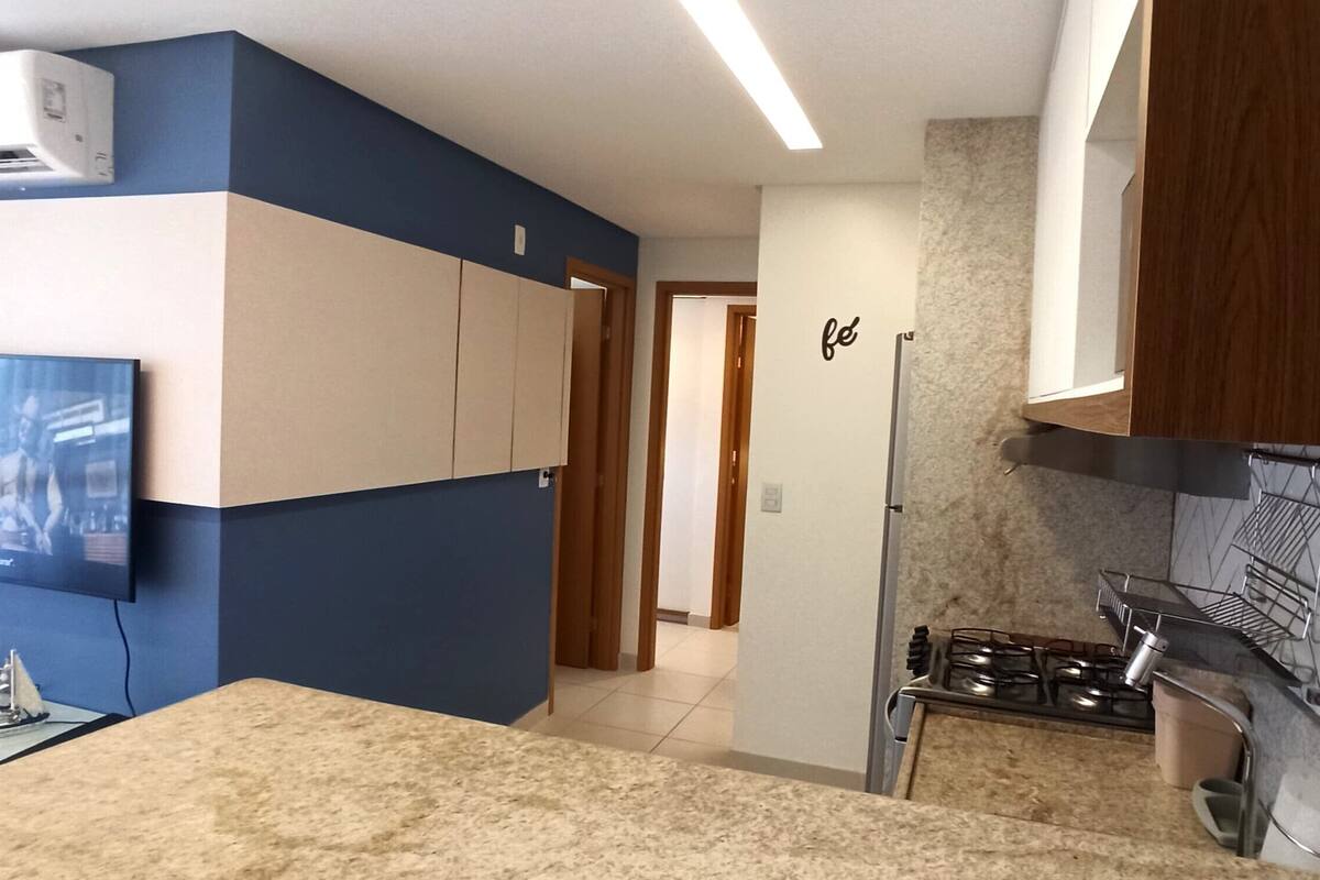 A modern kitchen with a built-in stove, a flat-screen TV, and a dining area with a glass table.