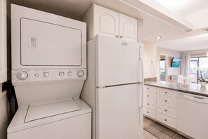 A kitchen with a built-in washer and dryer, a refrigerator, and a dining area with a view. - Park Shore Resort Charming 1st Floor-BLDG A #102 (Park Shore Resort)
