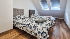 Un dormitorio con cama, dos mesitas de noche, una ventana y techo inclinado.