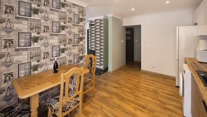 Una cocina moderna con una mesa y sillas de madera, un refrigerador y una pared con diseño de piedra, con letreros colgantes.