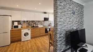 Una cocina moderna con armarios blancos, lavadora, microondas y cafetera.