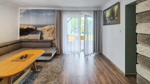 Una sala de estar moderna con un sofá modular, una mesa de centro de madera y un ventanal con cortinas translúcidas.