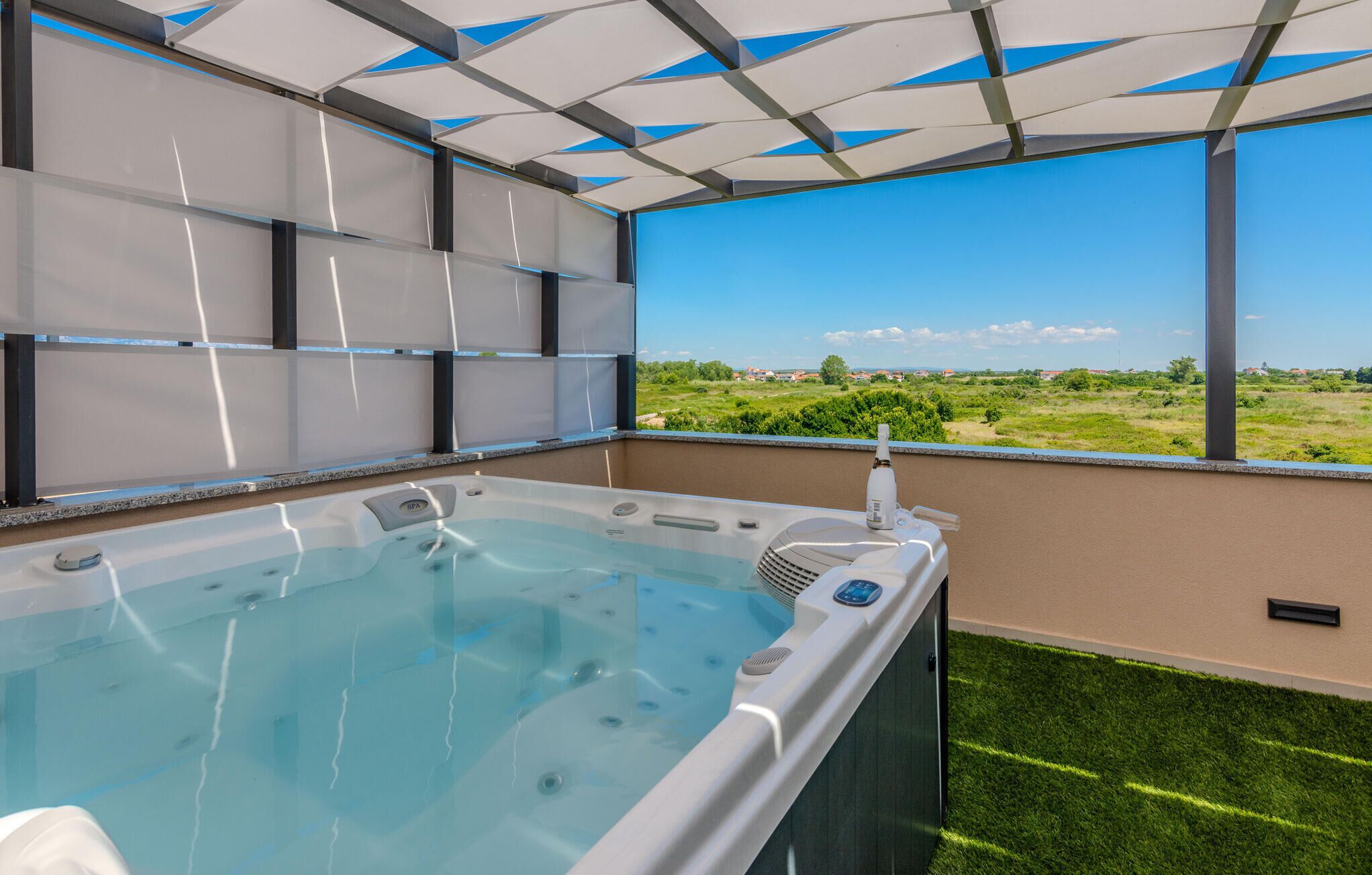A spa area with a hot tub, a view of the countryside, and a ceiling with geometric patterns.