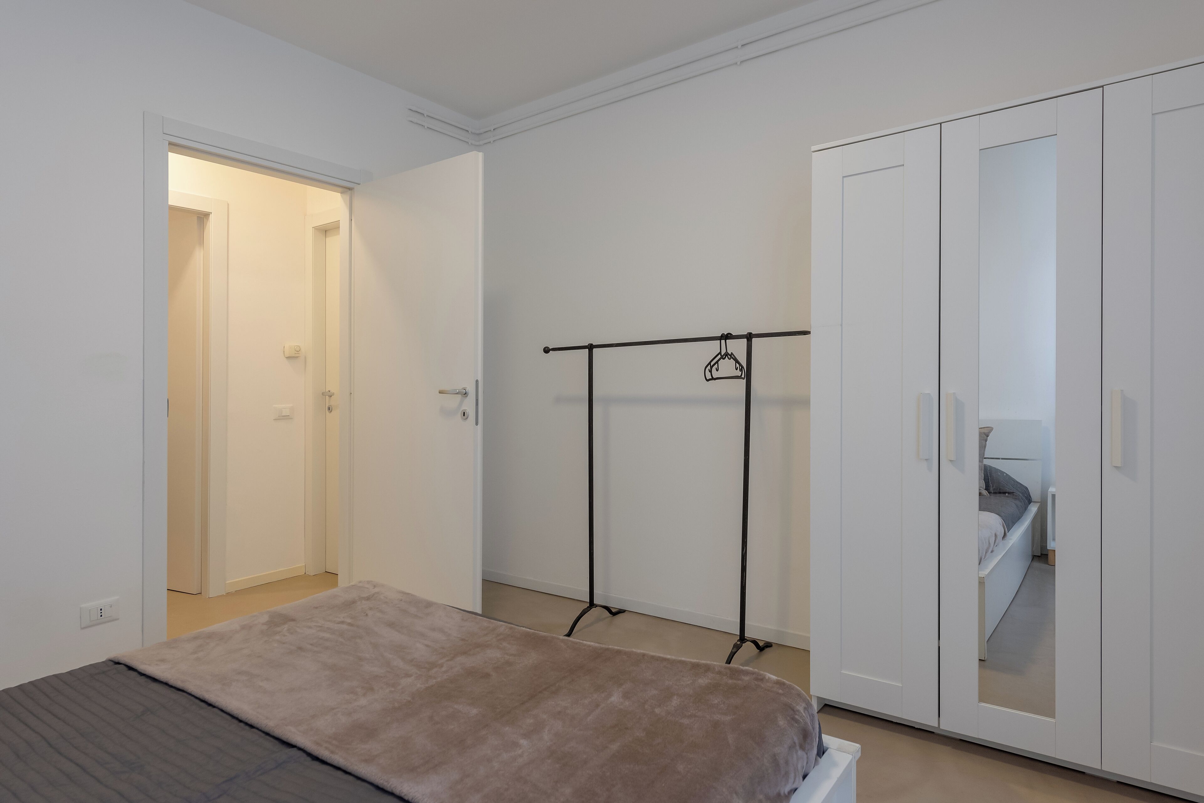 Un dormitorio con cama, armario y perchero.